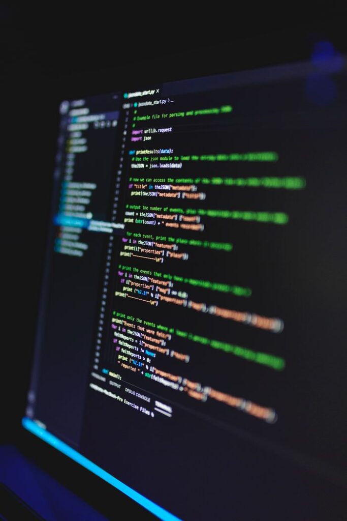 Vertical shot of colorful programming code on a screen in a dark room, highlighting technology work.